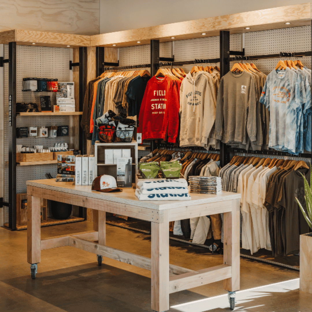 A shop display wooden shelves containing clothing, books and other accessories.